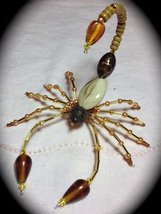 a spider made out of glass beads on a white tablecloth with gold colored accents