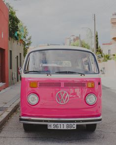 a pink vw bus parked on the street