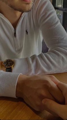 a man sitting at a table wearing a watch