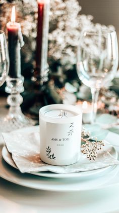 a white plate topped with a cup and saucer next to a candle on top of a table