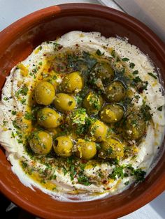 a bowl filled with hummus, olives and sour cream