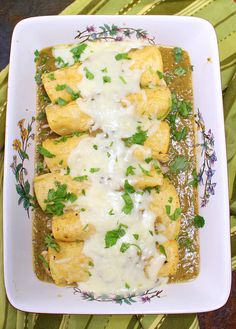 an enchilada dish is shown on a white plate with green garnish