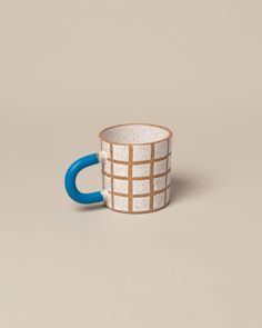 a white and blue coffee cup sitting on top of a table