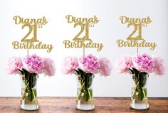 three vases with pink carnations and two happy 21st birthday cake toppers