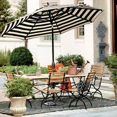 an outdoor dining table with chairs and umbrella