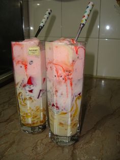 two glasses filled with liquid sitting on top of a counter