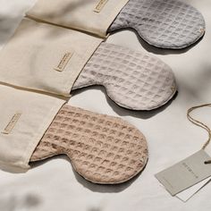 three pairs of oven mitts sitting on top of a white table next to a tag