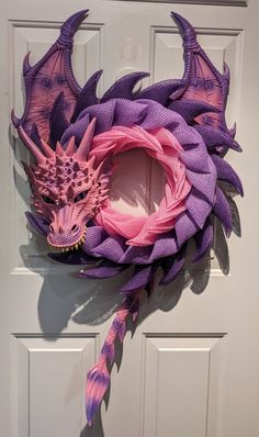 a purple and pink dragon wreath hanging on a door