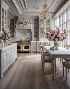 an elegant kitchen with white cabinets and pink flowers in vases on the dining room table