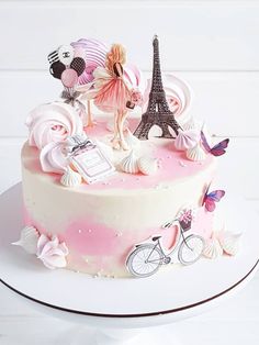 there is a cake with pink frosting and decorations on the top, including an eiffel tower in the background