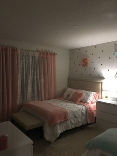 a bed room with a neatly made bed and pink curtains