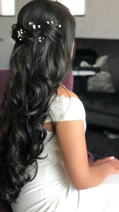 a woman sitting on top of a purple couch wearing a white dress and flowers in her hair