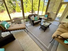 a living room filled with lots of furniture next to a large glass wall window covered in trees