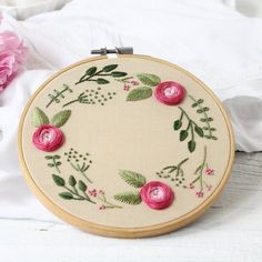 a close up of a embroidery on a piece of cloth with flowers in the background