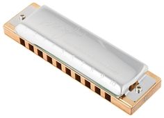 a harmonica is sitting on a white surface with gold trimmings and metal parts