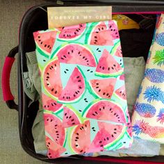 an open suitcase filled with watermelon paper and other items on top of it