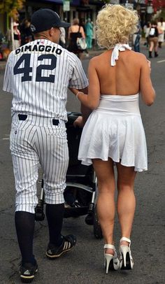 a man and woman in baseball uniforms walking down the street