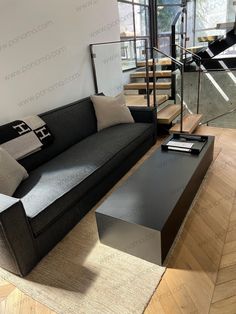 a living room with a couch, coffee table and stair case in the center area