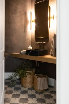 a bathroom with a sink, mirror and two baskets on the floor