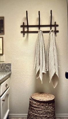 a bathroom with two towels hanging on the wall next to a basket and towel rack