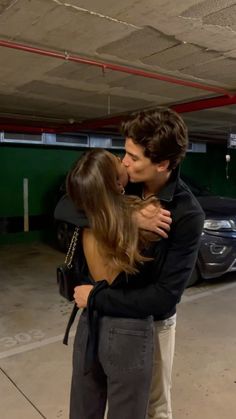 a man and woman kissing in a parking garage