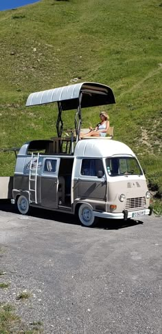 an old vw bus parked on the side of a road with a person sitting in it