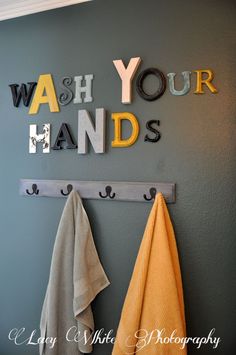 two towels hanging on a wall with the words wash your hands above them and below it is a towel rack