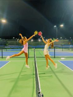 two women playing tennis in the rain at night