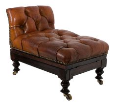 a brown leather chaise lounge chair on casteors with studded feet and wheels