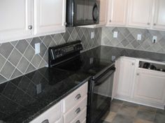 a kitchen with white cabinets and black counter tops is seen in this image, it appears to be empty