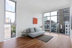 a living room with hardwood floors and large windows looking out onto the cityscape