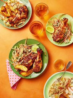 three plates of food on an orange table with utensils and glasses filled with drinks