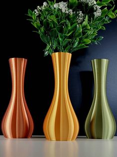 three different colored vases with flowers in them