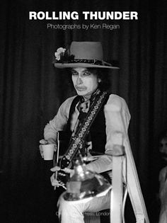 black and white photograph of a man with a hat holding a guitar in front of a stage