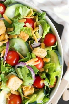 a salad with lettuce, tomatoes and croutons is shown in a bowl