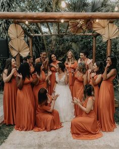 a group of bridesmaids in orange dresses standing around each other and holding umbrellas