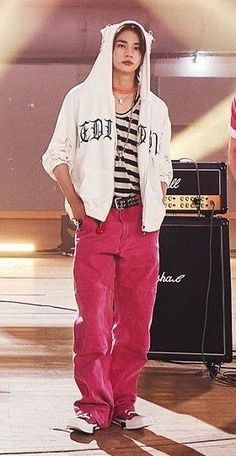 a young man standing on top of a stage wearing pink pants and a hoodie