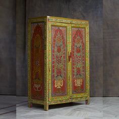 an ornately painted cabinet sits in front of a gray wall and wooden flooring