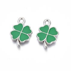 two clover shaped charms with green enamel on the side and one in the shape of a four leaf clover