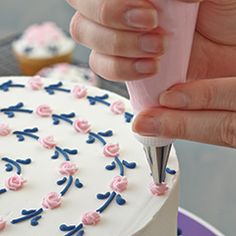 a person is cutting into a cake with pink and blue frosting on the icing