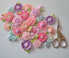 a bunch of crocheted flowers sitting next to a pair of scissors