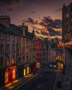 a city street with buildings lit up at night and clouds in the sky above it