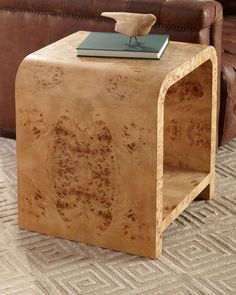 a wooden table sitting on top of a carpeted floor next to a brown couch