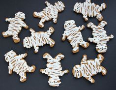 several decorated cookies with white icing on a black table top, one is cut in to look like dogs and the other looks like zebras