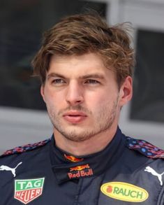 a close up of a person wearing a racing uniform and looking off to the side