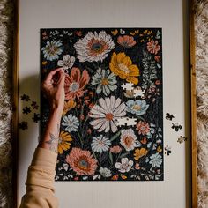 a person's hand is touching a puzzle with flowers on it