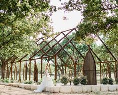 a bride and groom standing in front of a wooden structure at their outdoor wedding venue