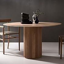 a wooden table with two chairs and a vase on it, in front of a gray wall