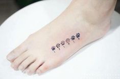 a small paw print tattoo on the left side of the foot, which has four flowers in different colors