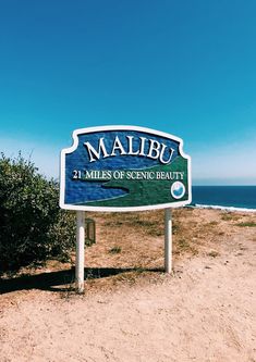 a sign that is on the side of a road near the beach and water in the background